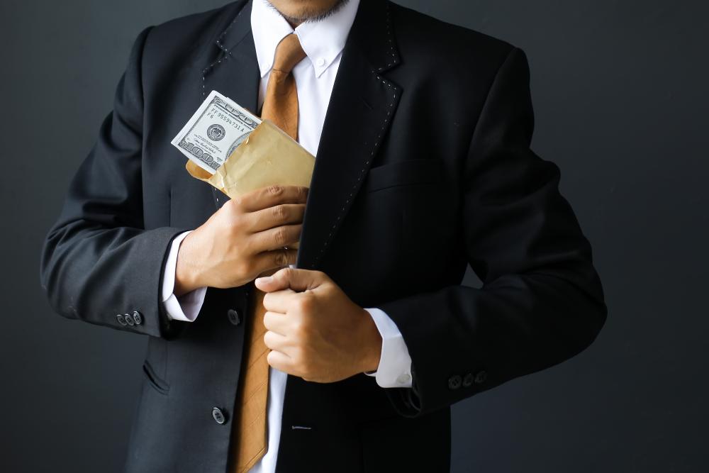 man putting dollar bills in suit pocket