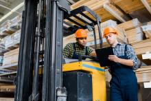 warehouse workers talking near forklift